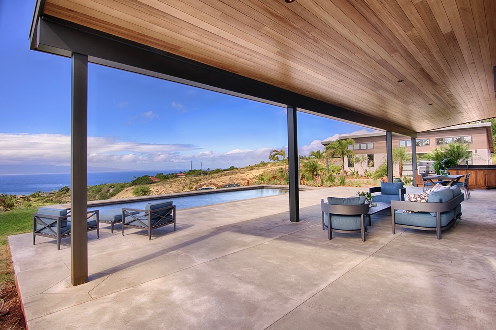 Large contemporary backyard patio in Hawaii with concrete slab and a roof extension.