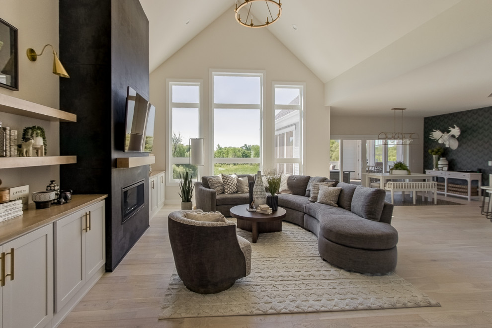 Country formal open concept living room in Other with beige walls, light hardwood floors, a standard fireplace, a stone fireplace surround, a wall-mounted tv, brown floor and vaulted.