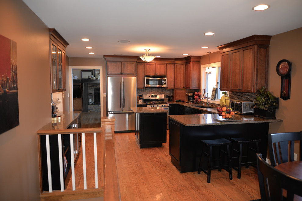 Open concept kitchen - mid-sized transitional u-shaped light wood floor open concept kitchen idea in Grand Rapids with an undermount sink, recessed-panel cabinets, black cabinets, quartzite countertops, multicolored backsplash, glass tile backsplash, stainless steel appliances and an island