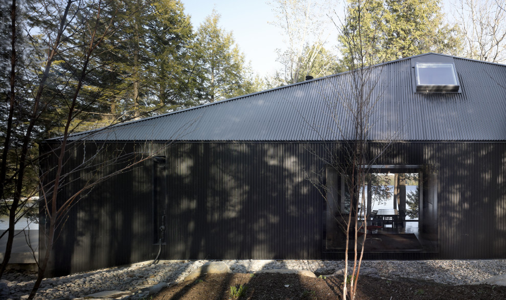 На фото: большой, одноэтажный, черный частный загородный дом в японском стиле в современном стиле с вальмовой крышей, металлической крышей, черной крышей и отделкой доской с нащельником