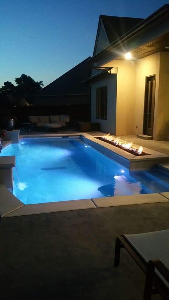 Photo of a mid-sized transitional backyard rectangular pool in Other with a water feature and concrete slab.