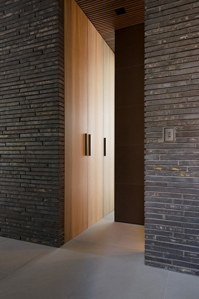 На фото: коридор в стиле модернизм с серыми стенами, полом из керамогранита, серым полом и кирпичными стенами