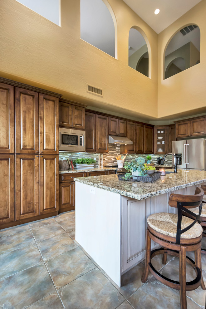 Example of a mid-sized transitional galley eat-in kitchen design in Phoenix with an undermount sink, raised-panel cabinets, medium tone wood cabinets, granite countertops, multicolored backsplash, glass tile backsplash, stainless steel appliances and an island