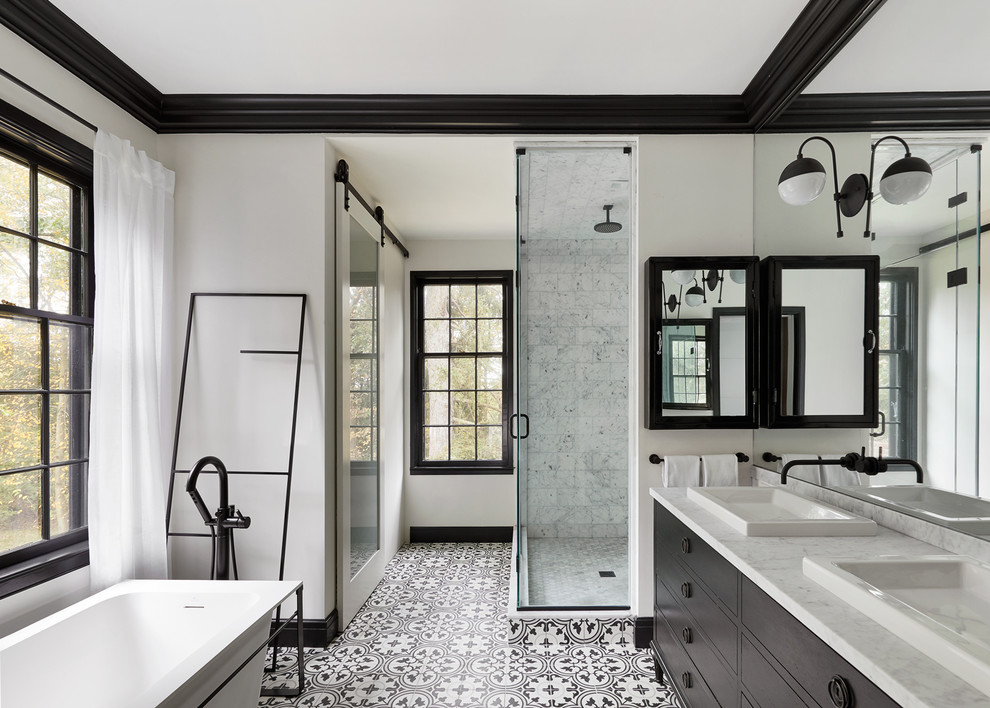 Design ideas for a transitional bathroom in New York with flat-panel cabinets, black cabinets, a freestanding tub, a corner shower, white tile, white walls, a drop-in sink, multi-coloured floor, a hinged shower door and white benchtops.