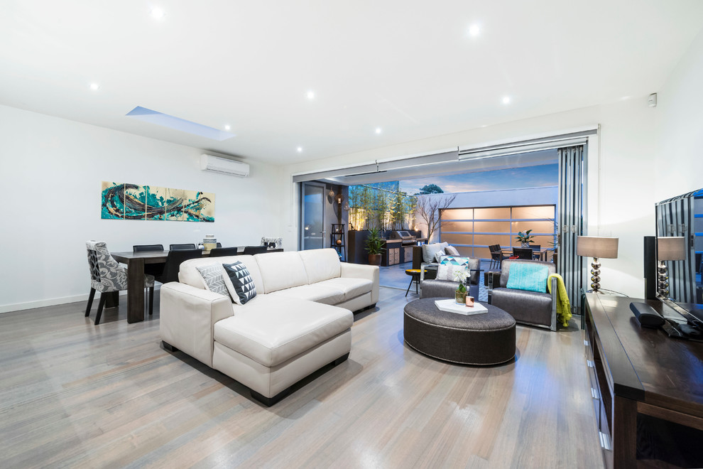 Mid-sized contemporary open concept living room in Melbourne with white walls, light hardwood floors and a freestanding tv.