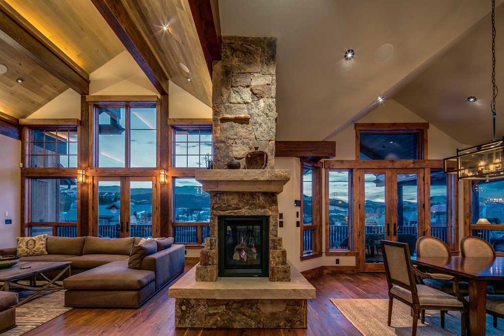 Photo of an expansive country open concept family room in Denver with a stone fireplace surround, a built-in media wall, white walls, dark hardwood floors and a corner fireplace.