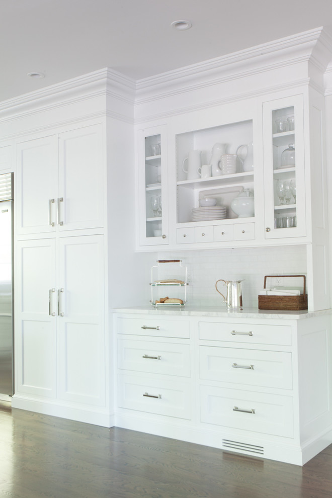 Inspiration for a mid-sized transitional l-shaped dark wood floor kitchen remodel in New York with beaded inset cabinets, white cabinets, marble countertops, white backsplash, subway tile backsplash, stainless steel appliances and an island
