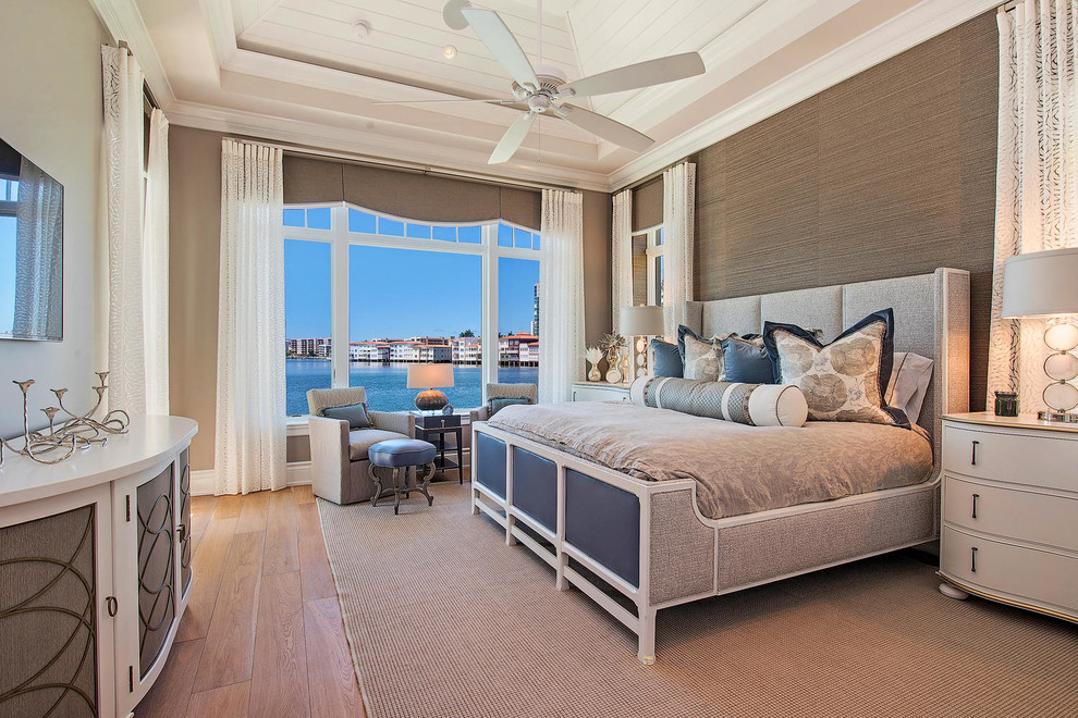 Photo of a large transitional master bedroom in Miami with beige walls, medium hardwood floors and brown floor.