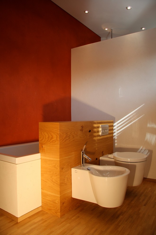 Mid-sized asian 3/4 bathroom in Munich with beaded inset cabinets, beige cabinets, a wall-mount toilet, red walls, light hardwood floors, a vessel sink, wood benchtops, beige floor, a drop-in tub, white tile and ceramic tile.