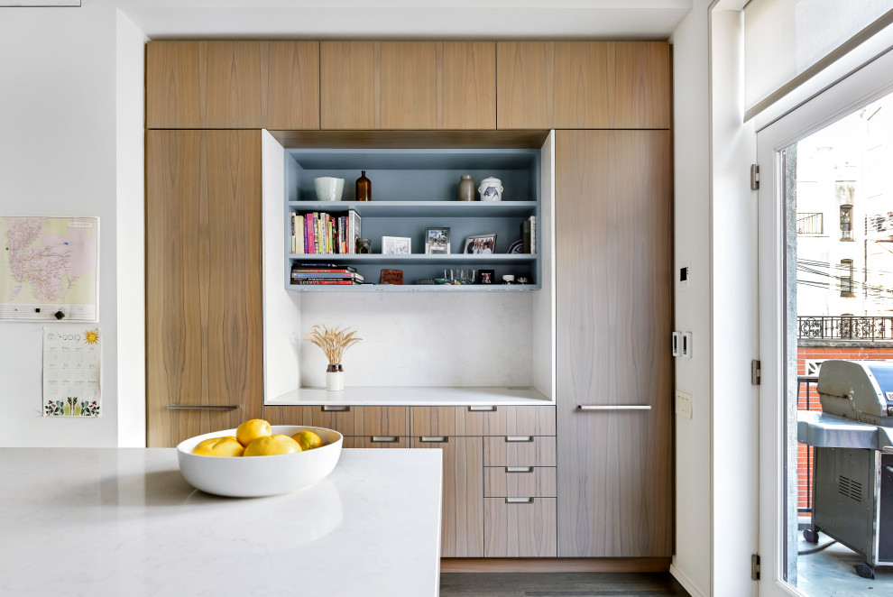 Bild på ett avskilt funkis vit vitt u-kök, med en undermonterad diskho, släta luckor, skåp i mellenmörkt trä, bänkskiva i kvarts, vitt stänkskydd, rostfria vitvaror, mellanmörkt trägolv, en köksö och brunt golv