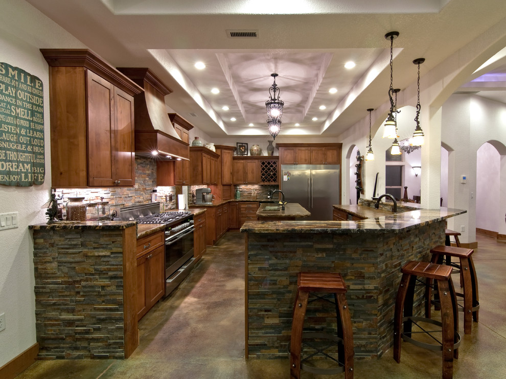 This is an example of an expansive mediterranean l-shaped open plan kitchen in Portland with an undermount sink, shaker cabinets, medium wood cabinets, concrete benchtops, brown splashback, subway tile splashback, stainless steel appliances, concrete floors, multiple islands, brown floor and brown benchtop.