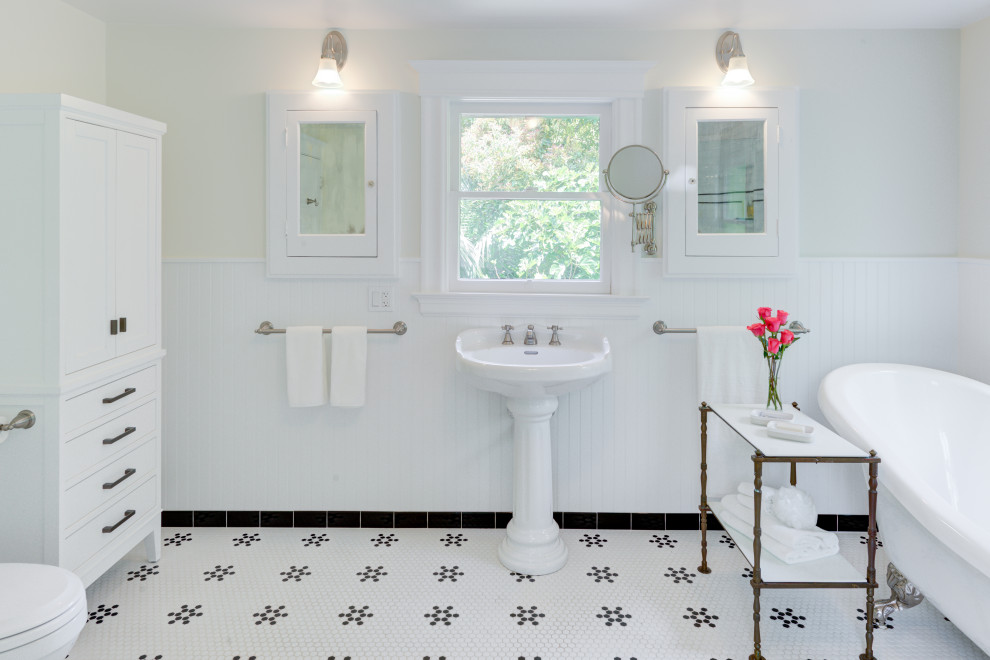 Источник вдохновения для домашнего уюта: большая главная ванная комната в классическом стиле с ванной на ножках, угловым душем, раздельным унитазом, белой плиткой, керамической плиткой, белыми стенами, полом из мозаичной плитки, раковиной с пьедесталом, белым полом, душем с распашными дверями, сиденьем для душа, тумбой под одну раковину и панелями на части стены