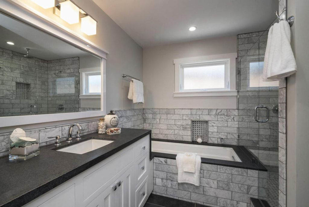 Inspiration for a mid-sized beach style master bathroom in Other with shaker cabinets, white cabinets, an undermount tub, a double shower, a one-piece toilet, gray tile, marble, grey walls, porcelain floors, an undermount sink, soapstone benchtops, black floor, an open shower and black benchtops.