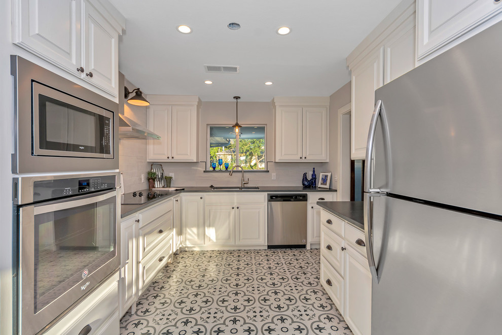 Inspiration for a small country galley eat-in kitchen in Dallas with an undermount sink, raised-panel cabinets, white cabinets, granite benchtops, grey splashback, ceramic splashback, stainless steel appliances, ceramic floors, multi-coloured floor and black benchtop.