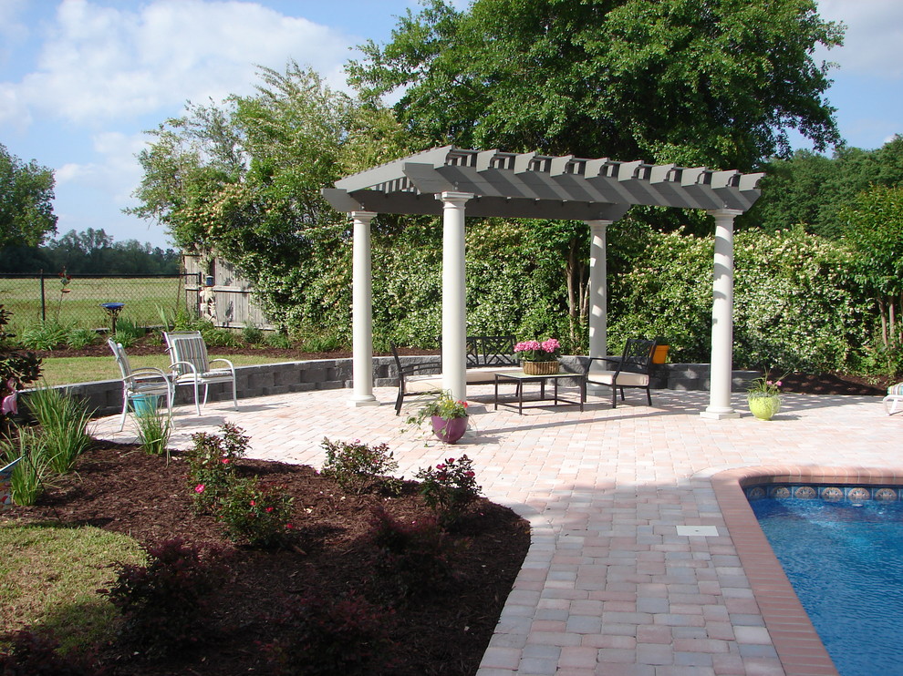 Design ideas for a large traditional backyard patio in Miami with concrete pavers and a pergola.