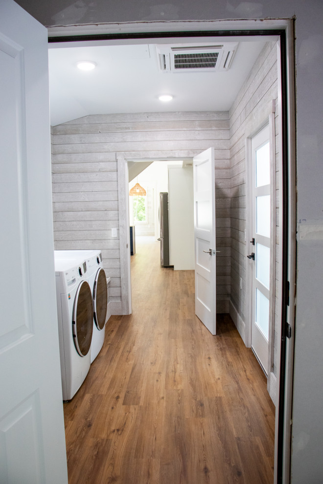 Inspiration for a mid-sized modern galley utility room in Grand Rapids with grey walls, laminate floors, a side-by-side washer and dryer, brown floor and planked wall panelling.