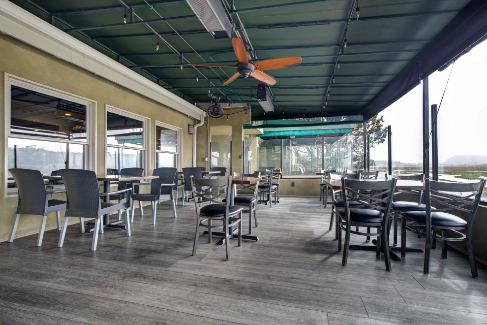 Foto di una grande sala da pranzo aperta verso il soggiorno costiera con pareti beige, pavimento in vinile, pavimento grigio e travi a vista