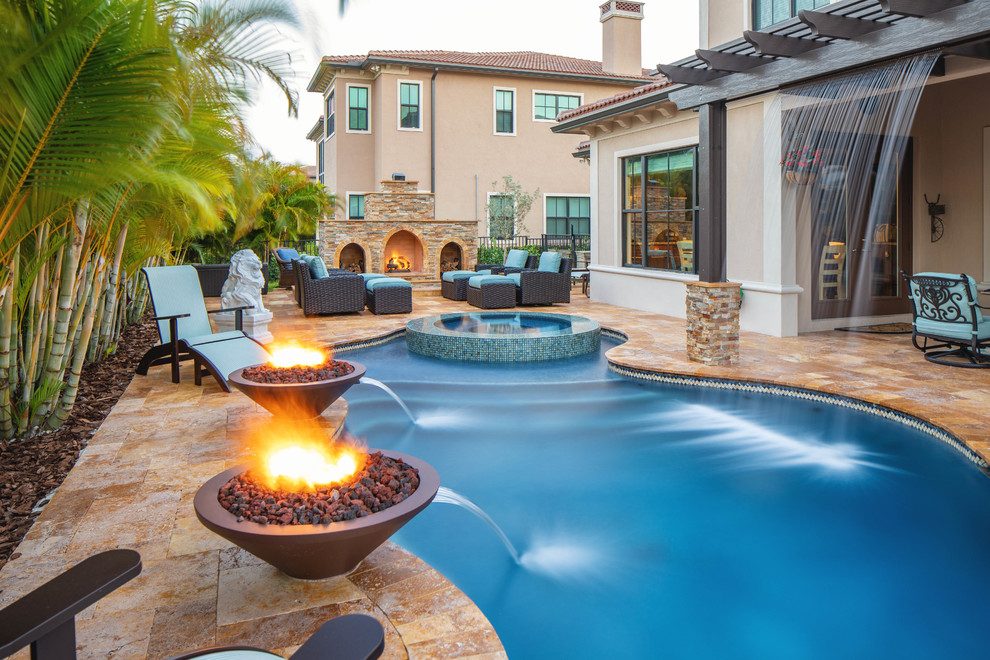 Photo of a large mediterranean backyard custom-shaped pool in Miami with a water feature and natural stone pavers.