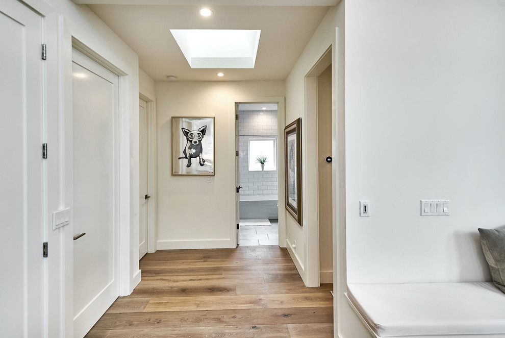 This is an example of a mid-sized modern hallway in San Francisco with white walls, light hardwood floors and beige floor.