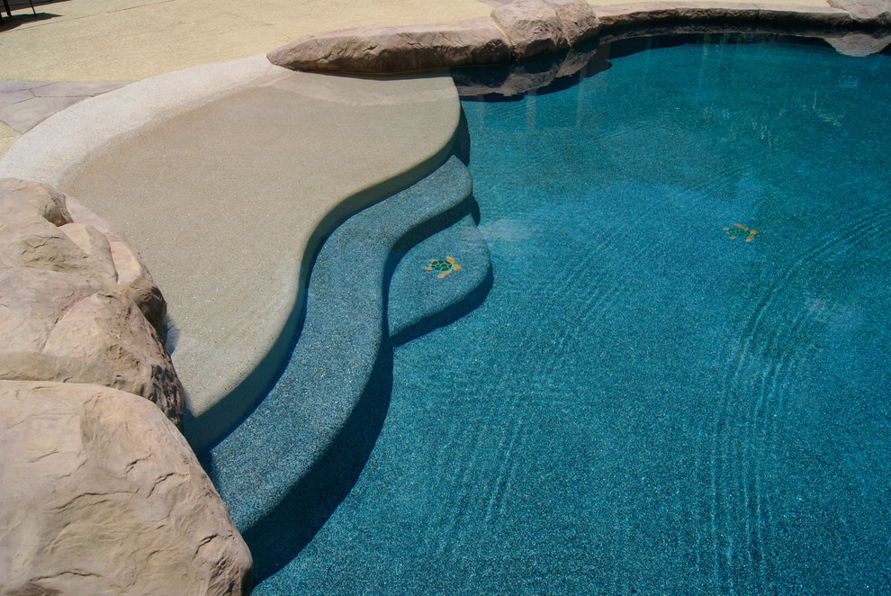 Photo of a mid-sized tropical backyard custom-shaped natural pool in Houston with a water slide and stamped concrete.