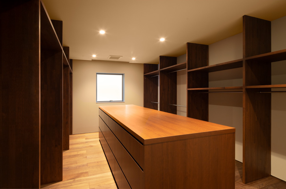 This is an example of a large modern gender-neutral storage and wardrobe in Fukuoka with open cabinets, dark wood cabinets, dark hardwood floors, brown floor and wallpaper.