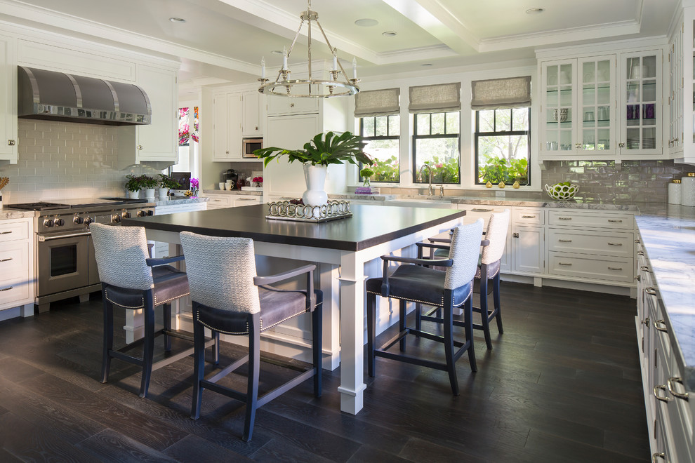 Example of a transitional dark wood floor eat-in kitchen design in Minneapolis with white cabinets, gray backsplash, stainless steel appliances and an island