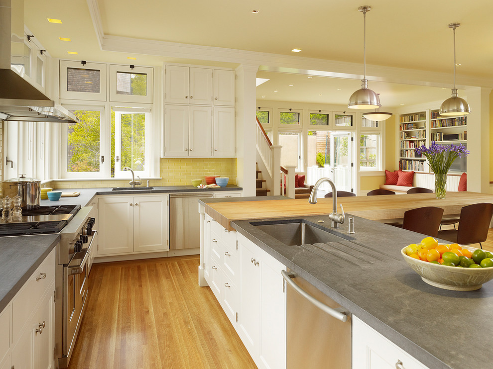Design ideas for a traditional u-shaped open plan kitchen in San Francisco with an undermount sink, shaker cabinets, white cabinets, concrete benchtops, yellow splashback, subway tile splashback, stainless steel appliances, light hardwood floors and with island.