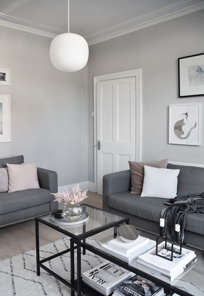 This is an example of a small scandinavian enclosed living room in Hampshire with grey walls, light hardwood floors and white floor.