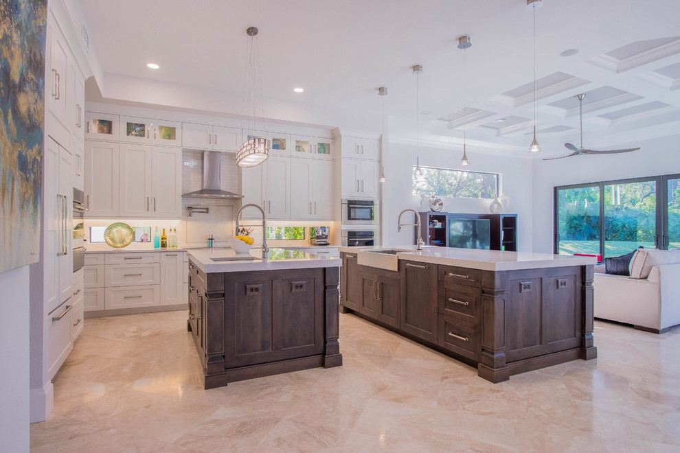 Example of a huge transitional l-shaped porcelain tile and beige floor open concept kitchen design with a farmhouse sink, shaker cabinets, white cabinets, quartz countertops, white backsplash, porcelain backsplash, stainless steel appliances and two islands