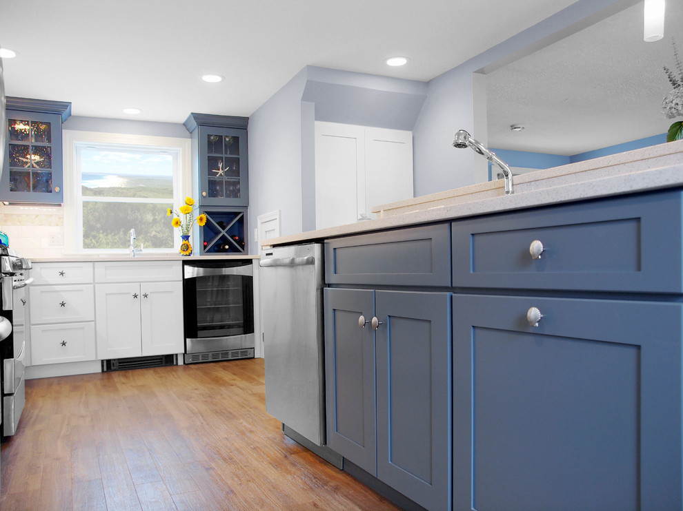 This is an example of a large beach style l-shaped eat-in kitchen in Boston with with island, shaker cabinets, blue cabinets, quartz benchtops, white splashback, subway tile splashback, stainless steel appliances and an undermount sink.