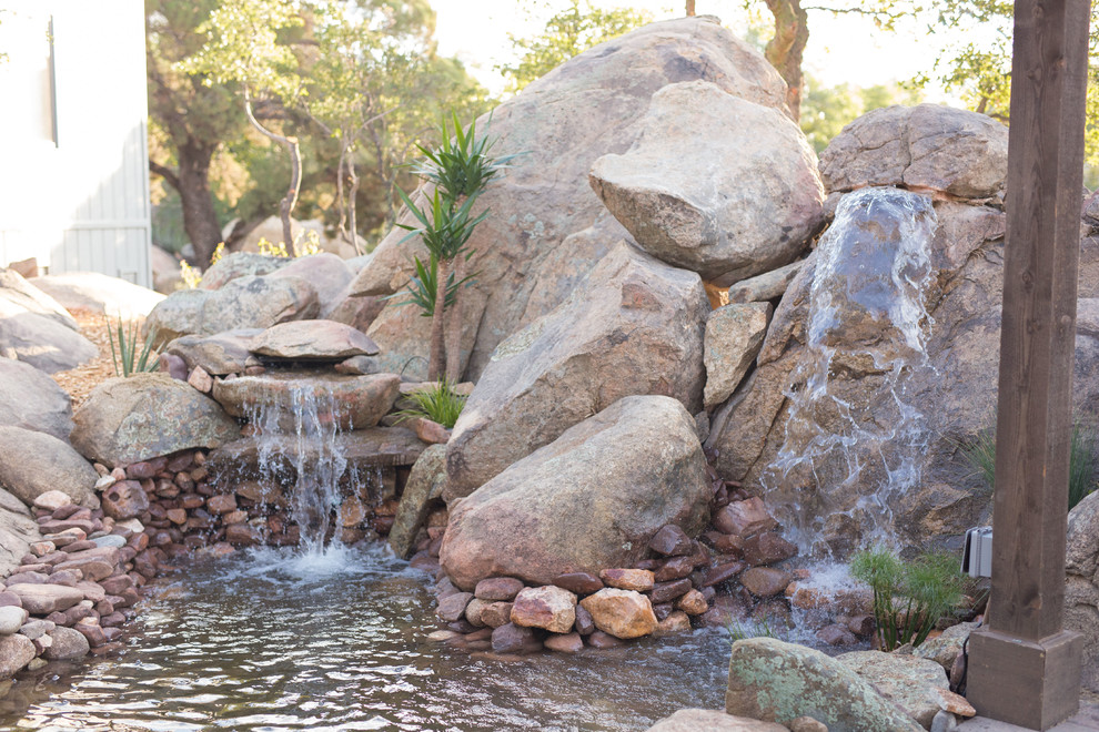 Design ideas for a large backyard partial sun garden in Phoenix with with pond and natural stone pavers.