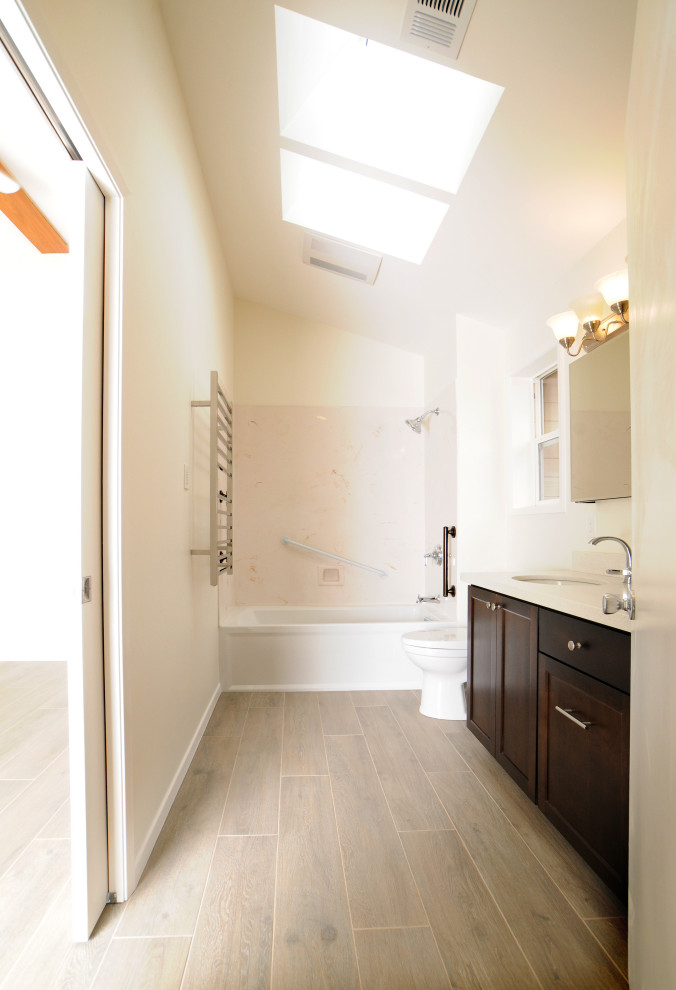 Photo of a small contemporary master bathroom in Other with shaker cabinets, dark wood cabinets, an alcove tub, a shower/bathtub combo, a two-piece toilet, white walls, porcelain floors, an undermount sink, engineered quartz benchtops, grey floor, white benchtops, a single vanity, a built-in vanity and vaulted.