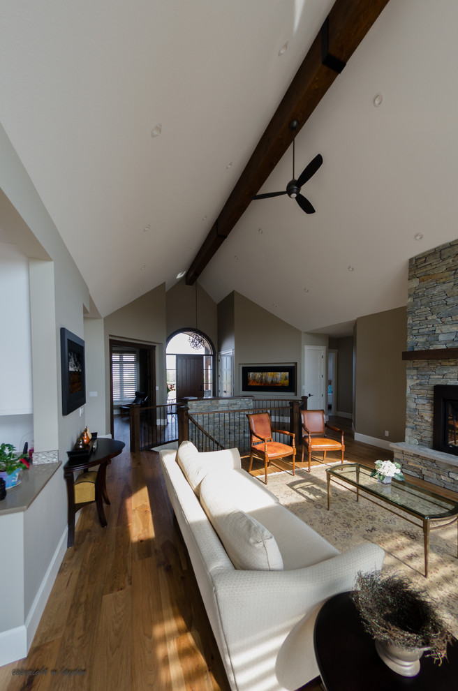 Photo of a mid-sized arts and crafts formal open concept living room in Calgary with medium hardwood floors, a standard fireplace, a stone fireplace surround, brown walls and no tv.