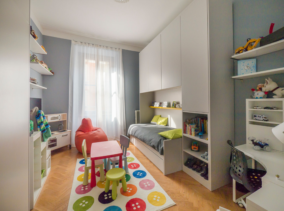 Large contemporary kids' bedroom in Milan with blue walls and light hardwood floors for kids 4-10 years old and boys.