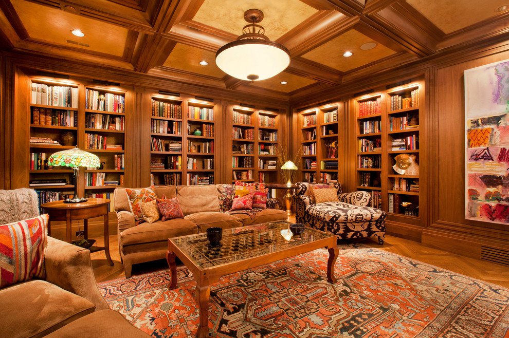 Large traditional family room in Omaha with a library, brown walls, a standard fireplace, a built-in media wall and medium hardwood floors.