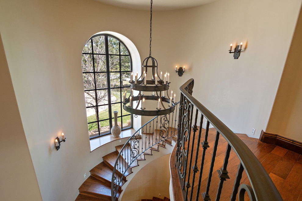 Photo of a large mediterranean wood curved staircase in San Diego with wood risers and metal railing.