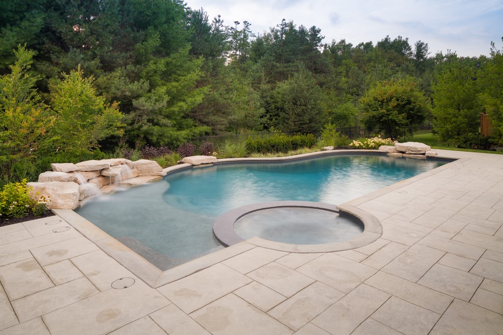 Inspiration for a large contemporary backyard custom-shaped natural pool in Toronto with a hot tub and stamped concrete.