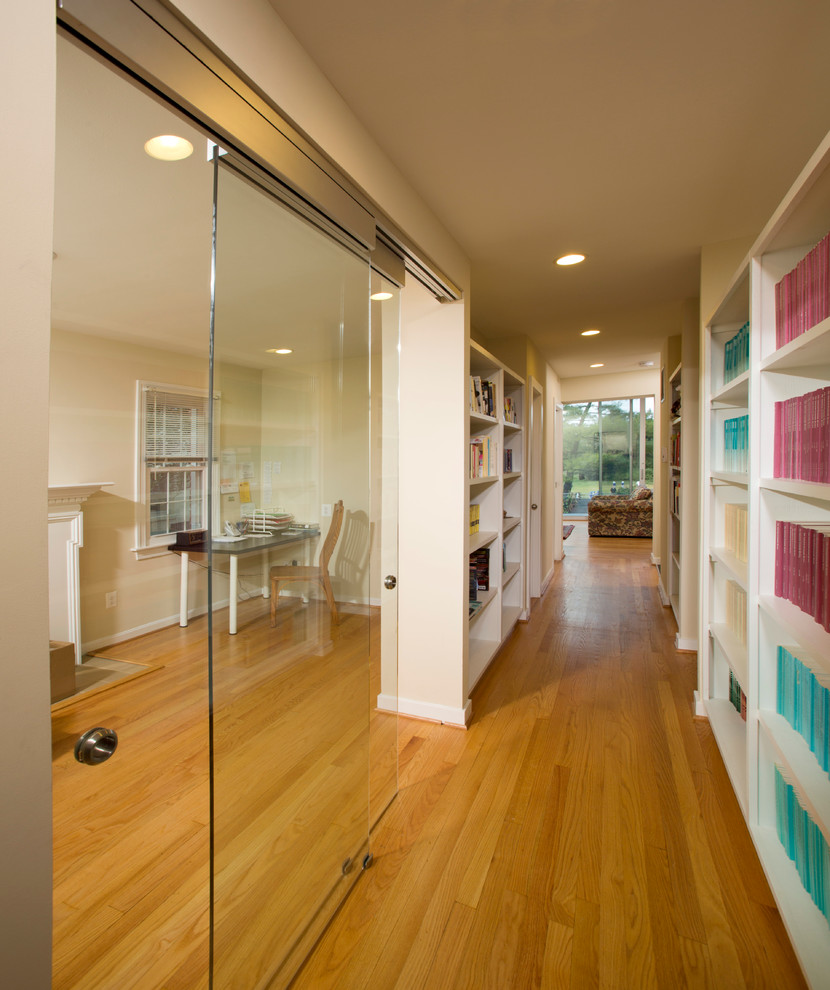 This is an example of a contemporary hallway in DC Metro with beige walls and light hardwood floors.