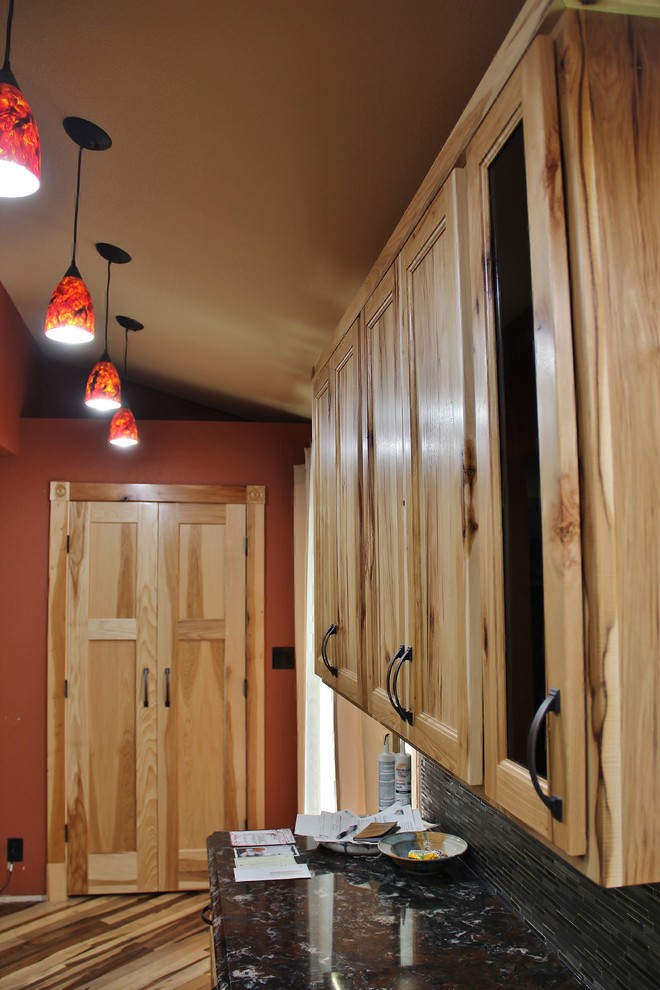 Example of a large mountain style l-shaped medium tone wood floor eat-in kitchen design in Minneapolis with an undermount sink, flat-panel cabinets, light wood cabinets, quartz countertops, black backsplash, glass tile backsplash, black appliances, red walls and no island