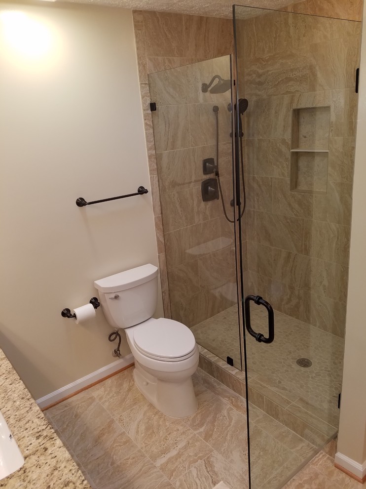 Design ideas for a traditional master bathroom in DC Metro with dark wood cabinets, a corner shower, beige tile, porcelain tile, beige walls, porcelain floors, an undermount sink, granite benchtops, beige floor and a hinged shower door.