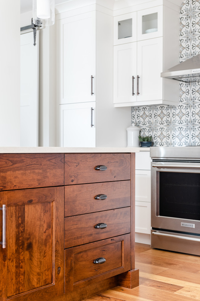 Kitchen pantry - mid-sized transitional l-shaped medium tone wood floor and brown floor kitchen pantry idea with an undermount sink, shaker cabinets, white cabinets, quartzite countertops, gray backsplash, porcelain backsplash, stainless steel appliances, an island and white countertops