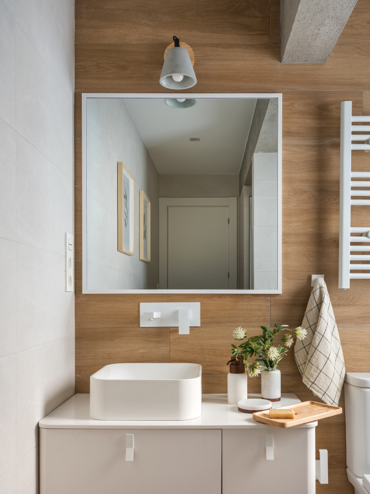 Inspiration for a small mediterranean ensuite bathroom in Bilbao with flat-panel cabinets, an alcove shower, a one-piece toilet, white tiles, ceramic tiles, grey walls, medium hardwood flooring, a vessel sink, onyx worktops, brown floors, a hinged door, white worktops, a single sink and a floating vanity unit.