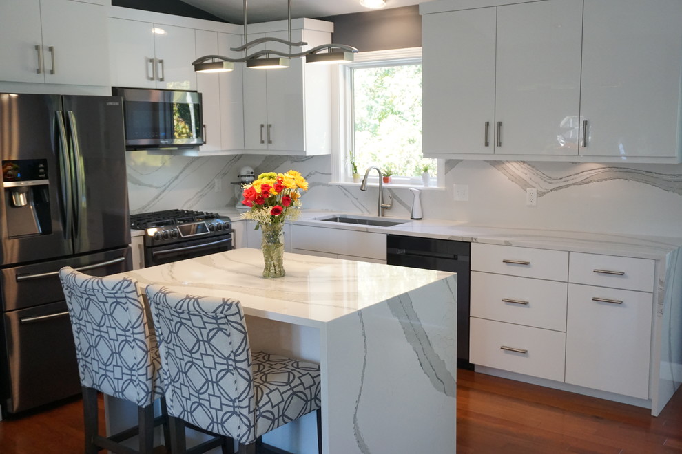 This is an example of a mid-sized contemporary l-shaped eat-in kitchen in Providence with an undermount sink, flat-panel cabinets, white cabinets, quartz benchtops, white splashback, stone slab splashback, stainless steel appliances, dark hardwood floors, with island, red floor and white benchtop.