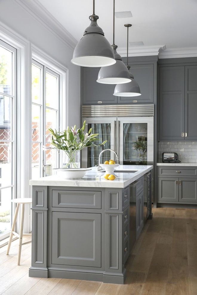 Inspiration for a transitional light wood floor kitchen remodel in Houston with an undermount sink, recessed-panel cabinets, gray cabinets, white backsplash, subway tile backsplash, stainless steel appliances, an island and white countertops