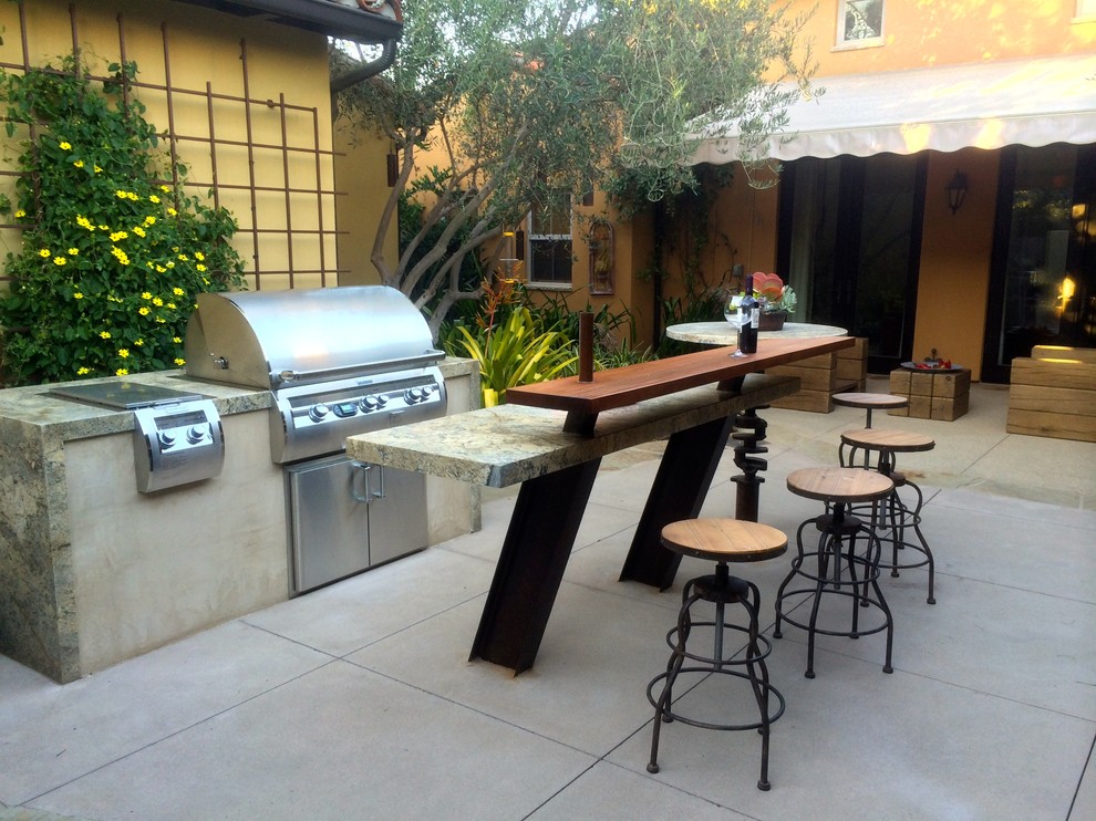 Photo of an eclectic courtyard patio in San Diego with concrete slab and an awning.