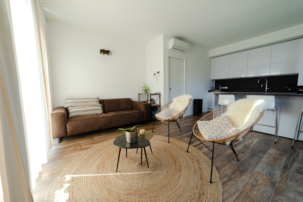 Foto de sala de estar con biblioteca abierta contemporánea de tamaño medio con paredes blancas, suelo de baldosas de porcelana, televisor en una esquina, suelo marrón y alfombra