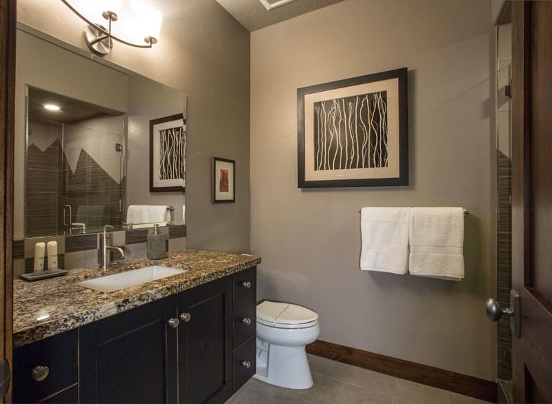 Photo of a mid-sized transitional 3/4 bathroom in Salt Lake City with shaker cabinets, dark wood cabinets, a two-piece toilet, brown walls, ceramic floors, an undermount sink, granite benchtops and brown floor.