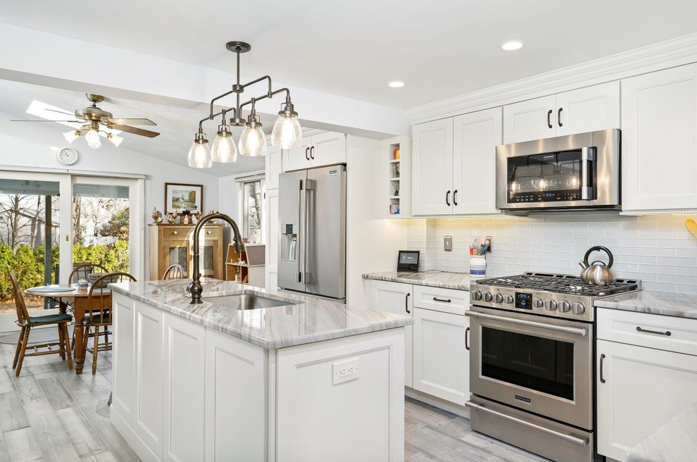 Photo of a mid-sized transitional kitchen in Providence with an undermount sink, shaker cabinets, white cabinets, marble benchtops, white splashback, glass tile splashback, stainless steel appliances, porcelain floors, with island, grey floor and multi-coloured benchtop.