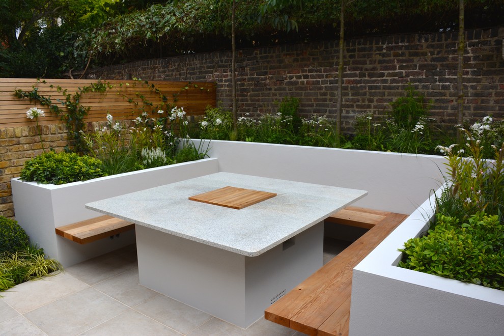 Inspiration for a small contemporary backyard patio in London with natural stone pavers.