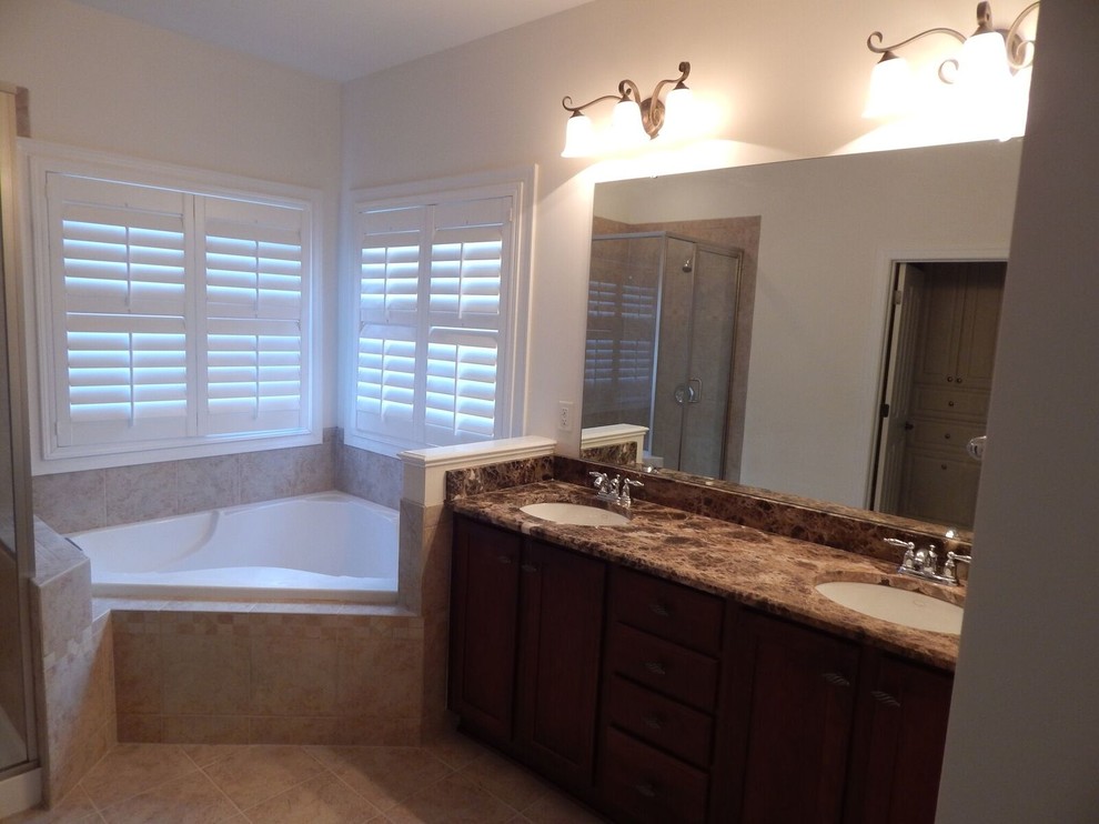 Inspiration for a mid-sized transitional master bathroom in Charlotte with shaker cabinets, dark wood cabinets, a drop-in tub, a corner shower, a two-piece toilet, brown tile, white walls, travertine floors, an undermount sink and soapstone benchtops.